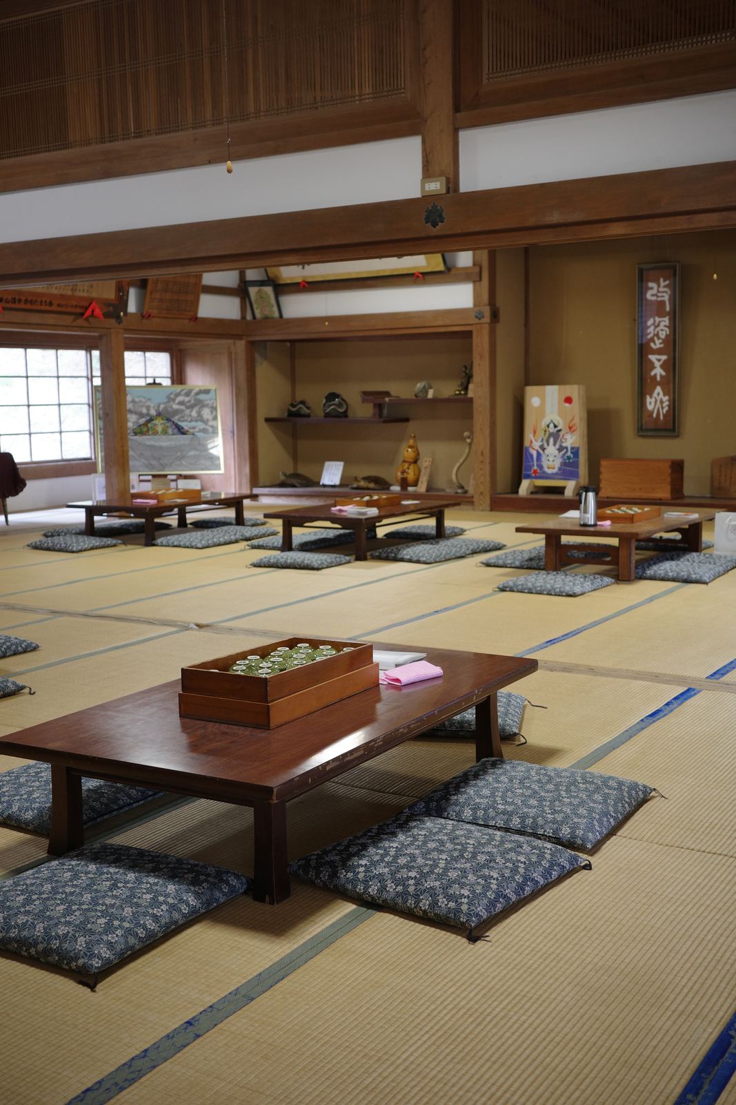 畳敷きの広い休憩所。座卓と座布団が並び、奥のテーブルに保温ポットとコップが置かれている