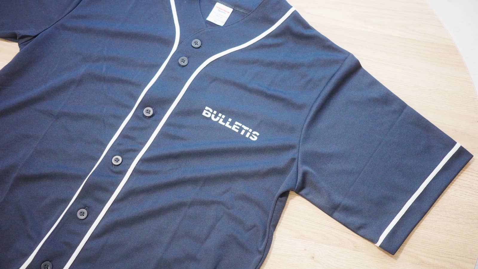 ネイビーのベースボールシャツの前面。左胸に白のBULLETISロゴが小さくプリントされている